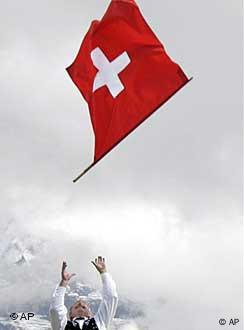 A man throws a Swiss flag in the air with a mountain backdrop