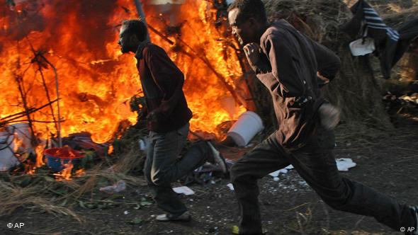 Displaced Somalis run past a burning tent during the attacks against immigrants in South Africa in 2008.