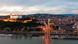 Bratislava at dusk, with Bratislava Castle illuminated, and the Danube river in the foreground.