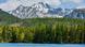 Strbske Pleso mountain lake, with dense spruce forest and steep mountains in the background.